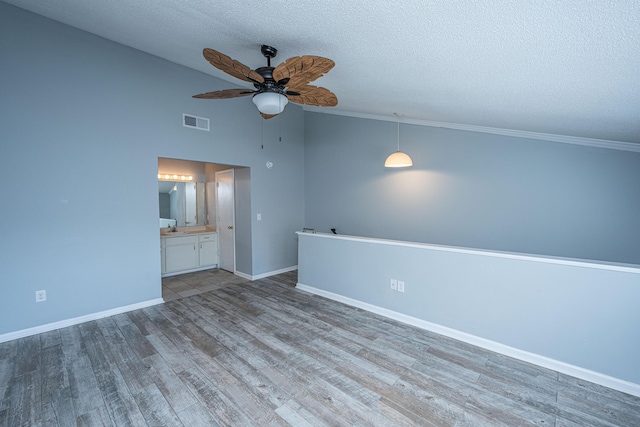 spare room with sink, ceiling fan, hardwood / wood-style floors, a textured ceiling, and vaulted ceiling