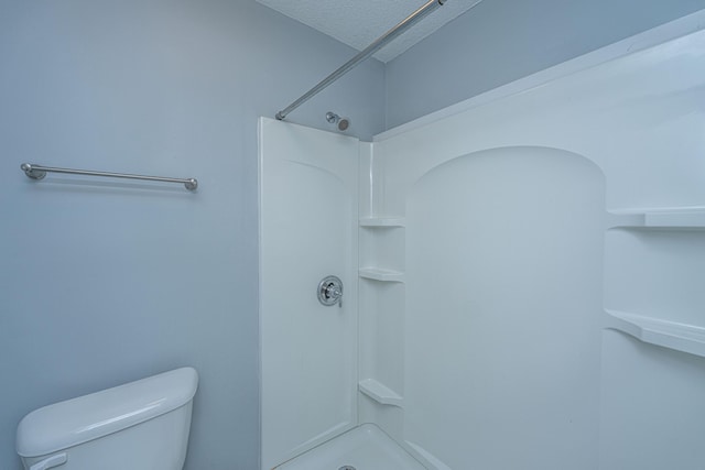 bathroom featuring a textured ceiling, toilet, and walk in shower