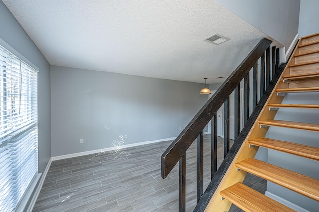 staircase with hardwood / wood-style floors and a textured ceiling