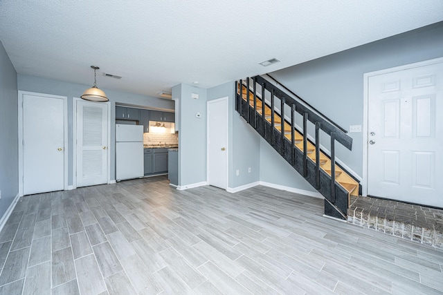 unfurnished living room with a textured ceiling and light hardwood / wood-style flooring