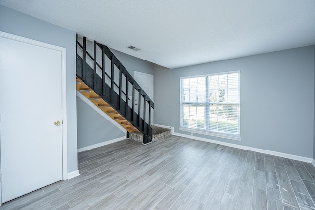 unfurnished living room with wood-type flooring and a textured ceiling