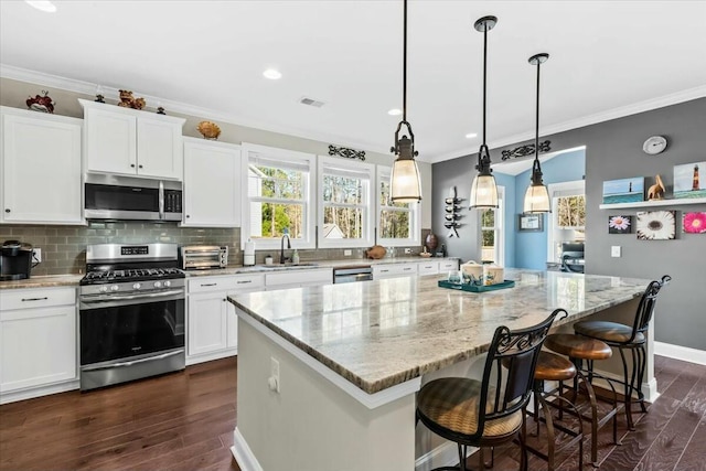 kitchen with a kitchen island, white cabinetry, appliances with stainless steel finishes, and sink