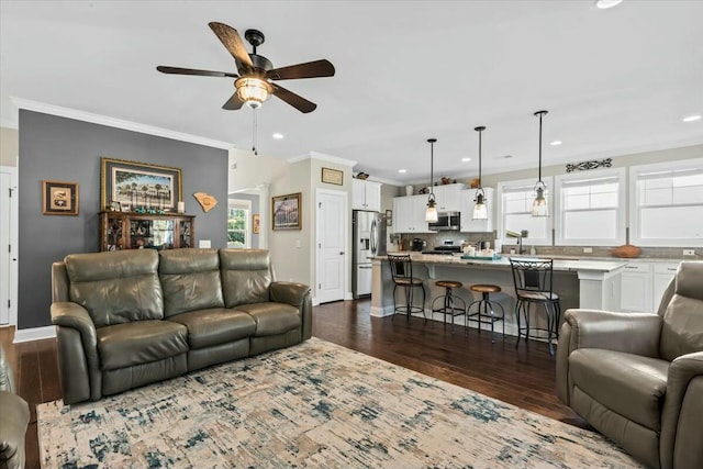 living room featuring dark wood-type flooring, ornamental molding, and plenty of natural light