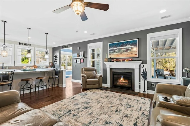 living room featuring ornamental molding, dark wood-type flooring, and ceiling fan