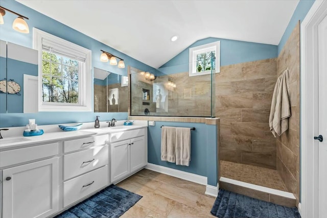 bathroom with vanity, vaulted ceiling, and a tile shower