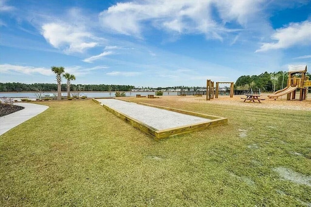 view of property's community with a playground, a water view, and a lawn