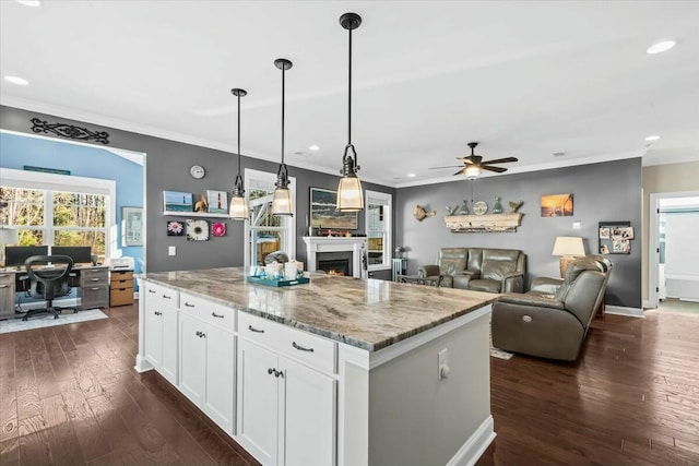 kitchen with a kitchen island, dark hardwood / wood-style floors, decorative light fixtures, white cabinets, and light stone countertops