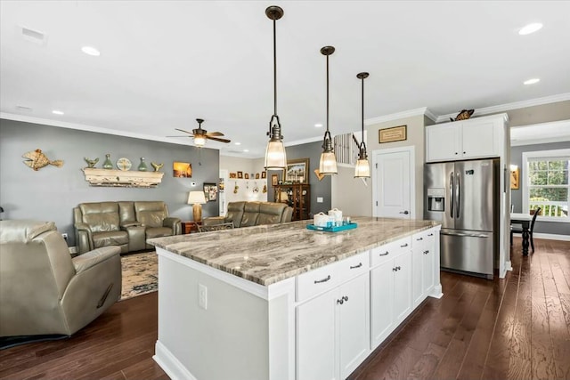 kitchen with stainless steel fridge, light stone countertops, white cabinets, a kitchen island, and decorative light fixtures