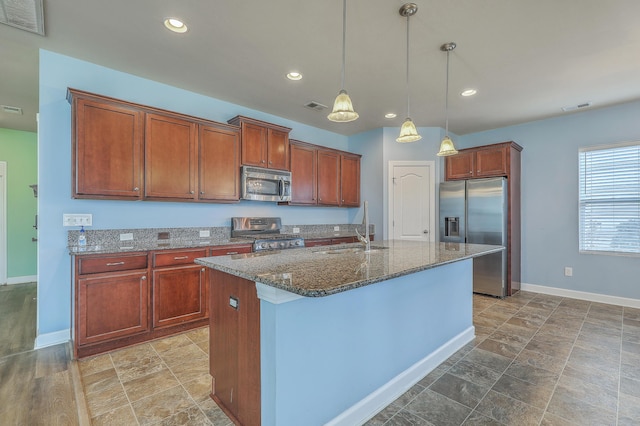 kitchen featuring stainless steel appliances, a sink, visible vents, dark stone countertops, and a center island with sink