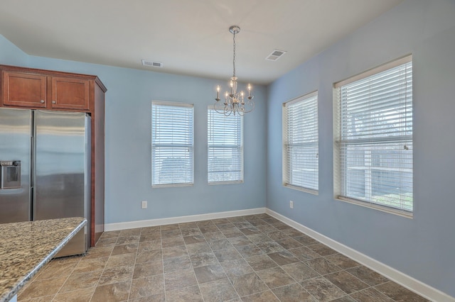 unfurnished dining area with visible vents, baseboards, and a notable chandelier