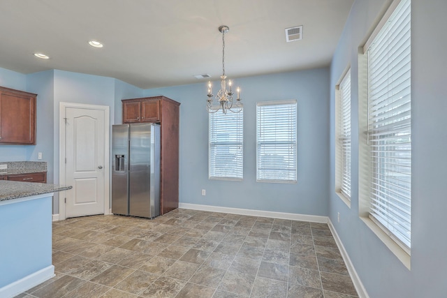 kitchen featuring brown cabinets, baseboards, pendant lighting, and stainless steel refrigerator with ice dispenser