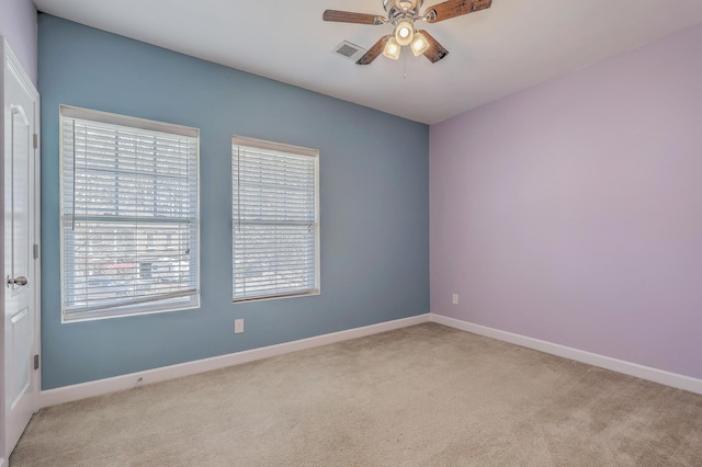 empty room with a ceiling fan, light carpet, visible vents, and baseboards