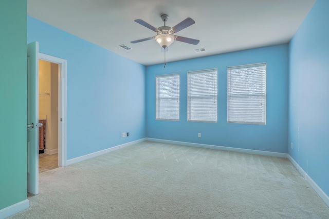 unfurnished room with baseboards, a ceiling fan, visible vents, and light colored carpet