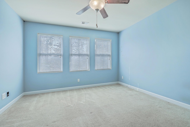 spare room with ceiling fan, baseboards, and light colored carpet