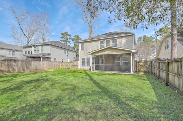 rear view of house with a sunroom, a fenced backyard, and a lawn