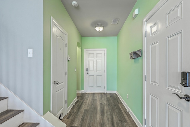 hallway featuring dark wood-style floors, arched walkways, visible vents, baseboards, and stairs