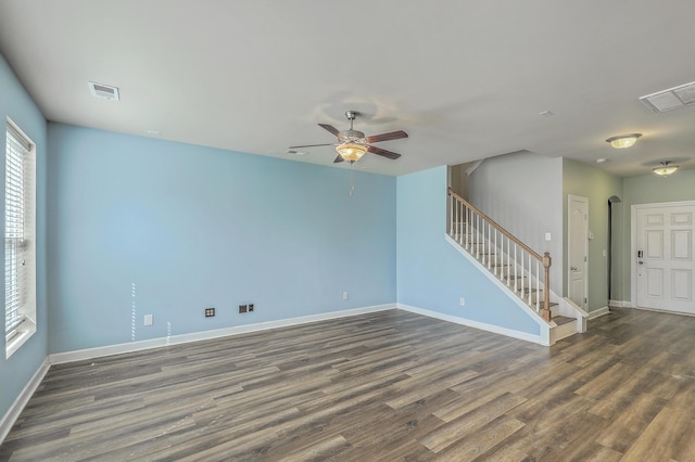 empty room with dark wood-style floors, visible vents, and stairs