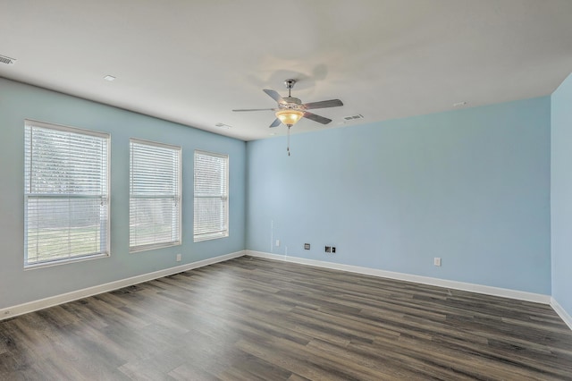 spare room featuring a ceiling fan, baseboards, visible vents, and dark wood-type flooring