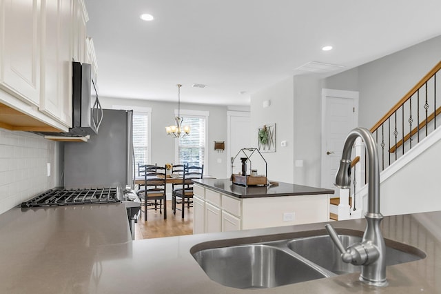 kitchen featuring sink, white cabinetry, pendant lighting, stainless steel appliances, and backsplash