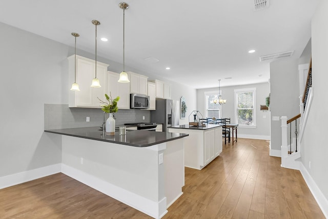 kitchen with pendant lighting, appliances with stainless steel finishes, white cabinetry, decorative backsplash, and kitchen peninsula