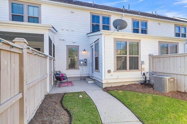 back of property with a lawn, cooling unit, and a patio area