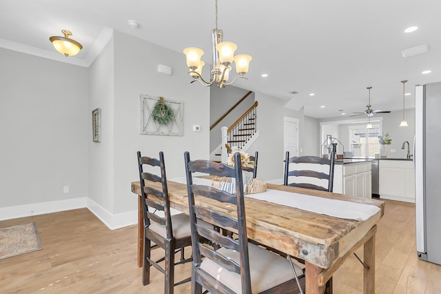 dining space featuring sink, crown molding, ceiling fan with notable chandelier, and light wood-type flooring