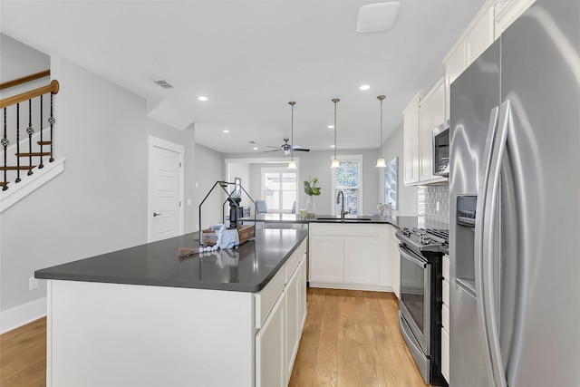 kitchen with pendant lighting, white cabinetry, stainless steel appliances, a center island, and kitchen peninsula