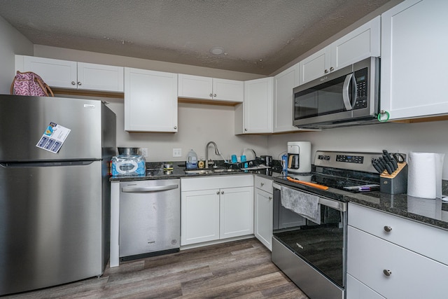 306 Crestview Dr Unit C, Summerville, SC 29485 - kitchen featuring appliances with stainless steel finishes, dark wood-type flooring, white cabinetry, a sink, and dark stone counters