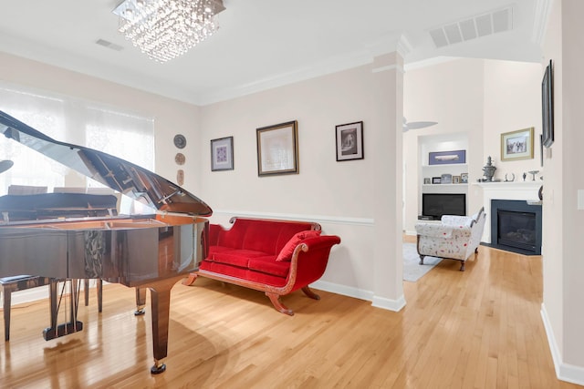 sitting room featuring visible vents, baseboards, hardwood / wood-style floors, and a glass covered fireplace