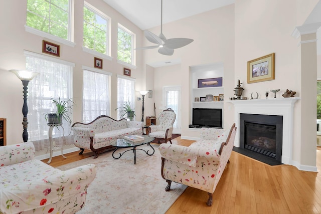 living area with a ceiling fan, plenty of natural light, and wood finished floors