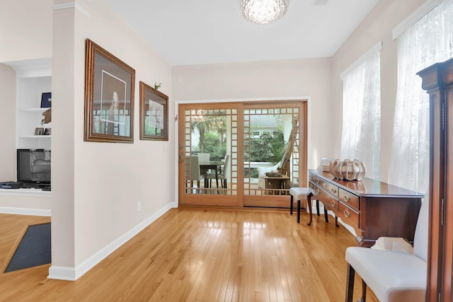 interior space with light wood-style floors, baseboards, and an inviting chandelier