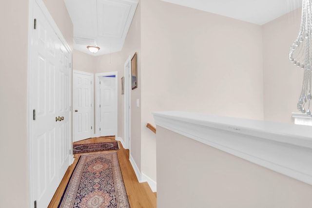 hallway featuring light wood-style floors, baseboards, and attic access