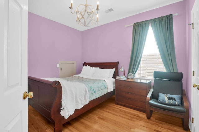 bedroom with visible vents, an inviting chandelier, and wood finished floors