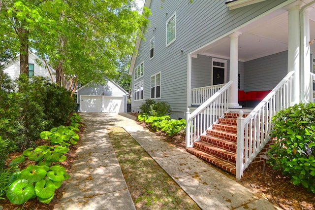 view of property exterior with a detached garage, a porch, and an outdoor structure