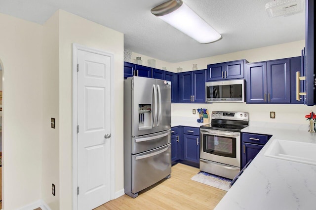 104 Lancaster Ct, Goose Creek, SC 29445 - kitchen with appliances with stainless steel finishes, blue cabinets, light wood-style floors, light stone countertops, and a textured ceiling