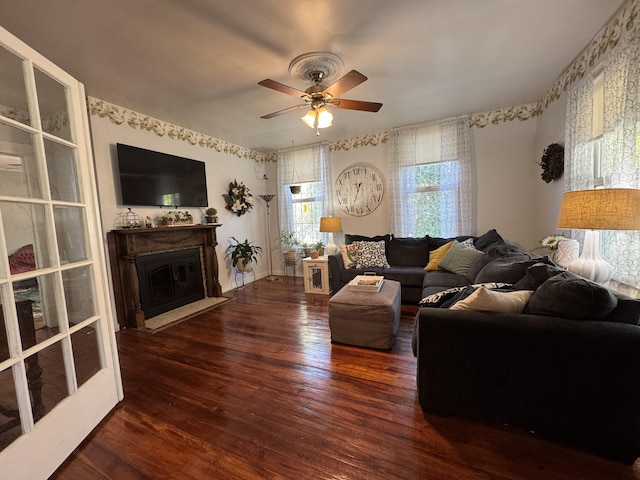 living area with wood finished floors, ceiling fan, a glass covered fireplace, and wallpapered walls