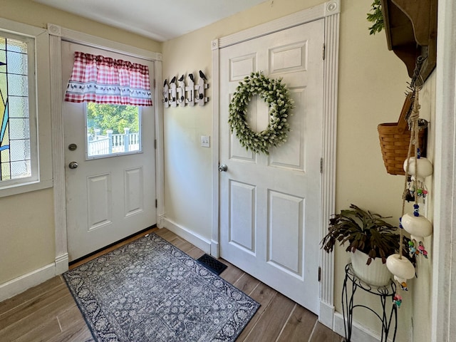 foyer with healthy amount of natural light, wood finished floors, and baseboards
