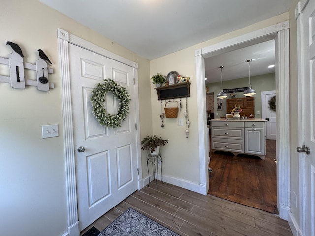 entryway with dark wood finished floors and baseboards