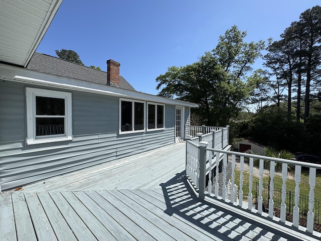 wooden deck featuring a storage shed and an outdoor structure