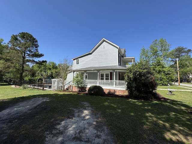 view of side of home featuring covered porch, a lawn, and crawl space