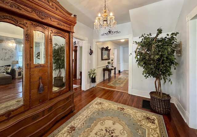 foyer featuring dark wood-style flooring, a chandelier, and baseboards