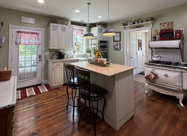 kitchen with light countertops, a breakfast bar area, dark wood-type flooring, a center island, and recessed lighting