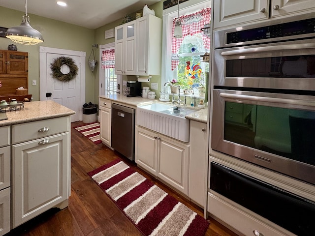 kitchen with stainless steel appliances, a warming drawer, dark wood-style floors, white cabinets, and decorative light fixtures