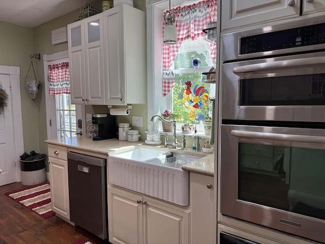 kitchen featuring dishwashing machine, stainless steel double oven, a sink, dark wood finished floors, and white cabinets