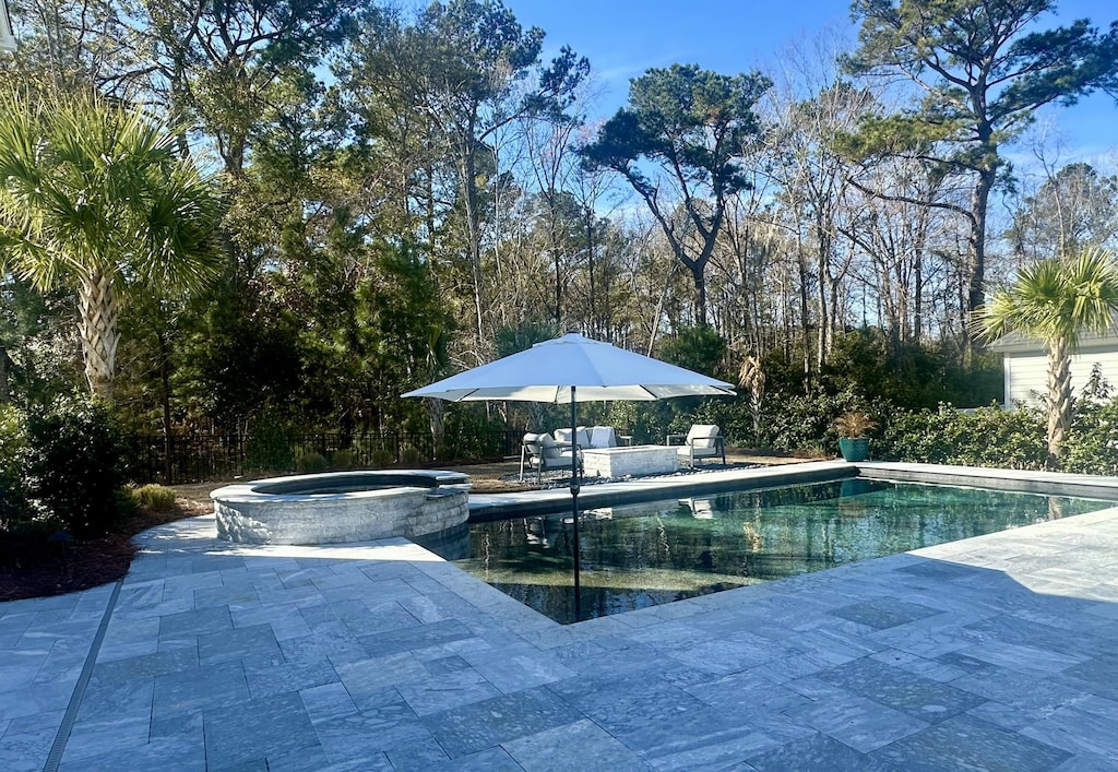 view of pool featuring a patio area and an in ground hot tub