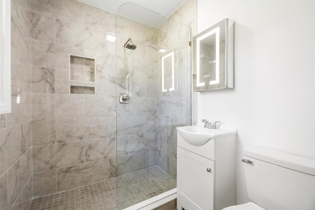 bathroom featuring vanity, toilet, and a tile shower