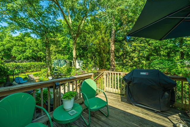 wooden deck featuring a storage unit and area for grilling