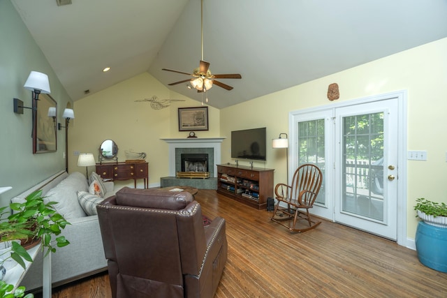 living room featuring ceiling fan, a tiled fireplace, dark wood-type flooring, and vaulted ceiling