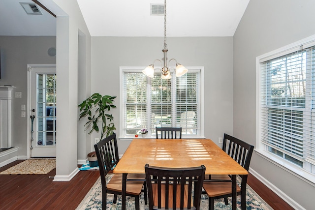 dining space with a chandelier, vaulted ceiling, a wealth of natural light, and dark wood-type flooring