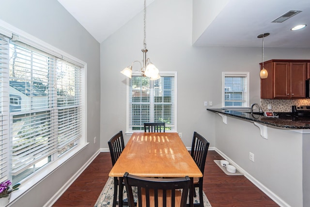 dining room with lofted ceiling, sink, dark hardwood / wood-style floors, and a notable chandelier